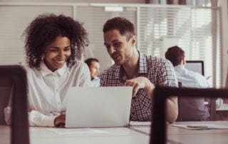Man and woman pointing at a laptop