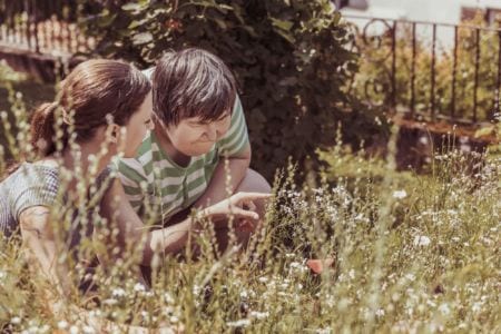 A young woman showing an older woman flowers in a garden