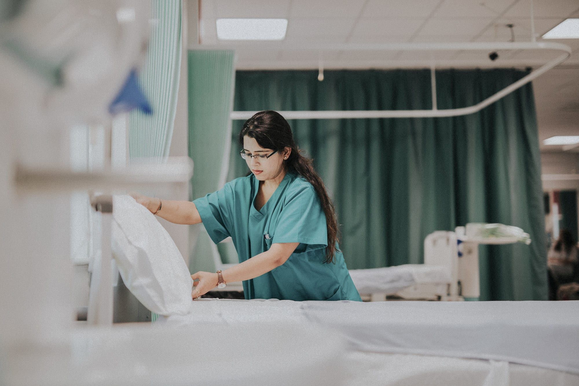 A nurse making a bed in a hospital