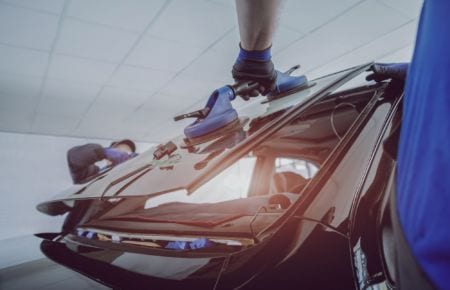 Two people removing the windshield of a car