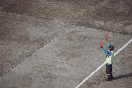An aviation ground specialist signaling on a runway