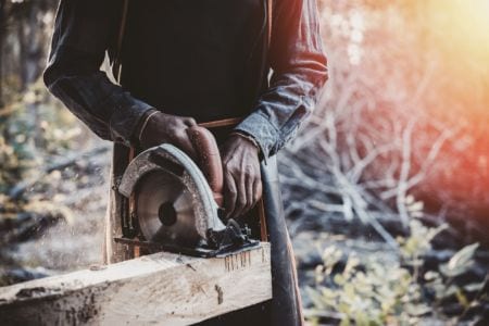 A man sawing through a wooden beam