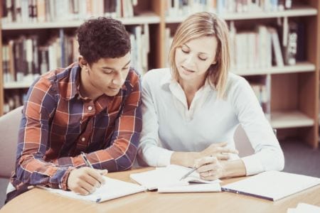 A young man and a woman looking at a notebook
