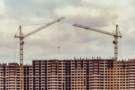 Two tall cranes above a building in construction