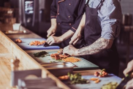 Two chefs dicing peppers in a kitchen