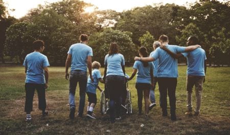 A group of people in blue shirts walking together away from the camera