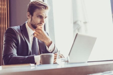 A man in a suit looking at a computer screen