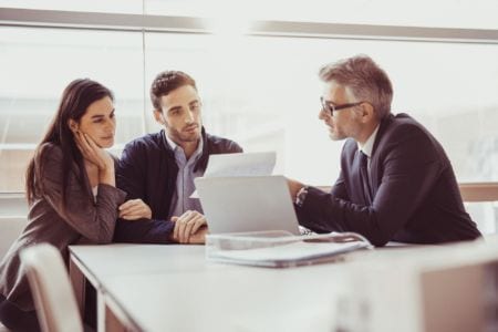 Three people in a meeting looking at some papers
