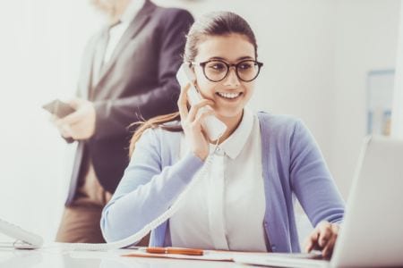 A smiling woman on the phone looking at a screen