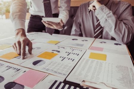 A person showing plans on the table to his colleague