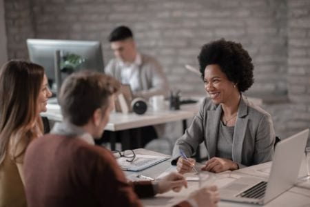 A young woman smiling and consulting a young couple