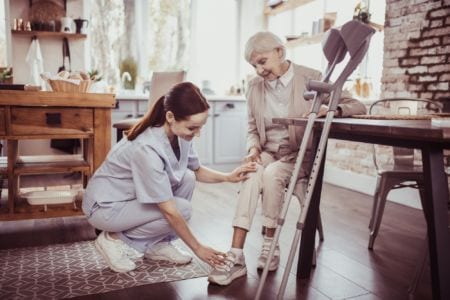 A nurse checking the shoes of a elderly woman