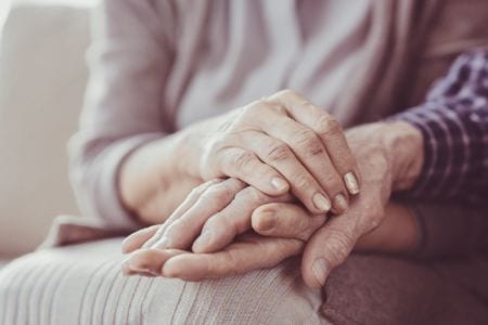 A woman holding the hand of an elderly man