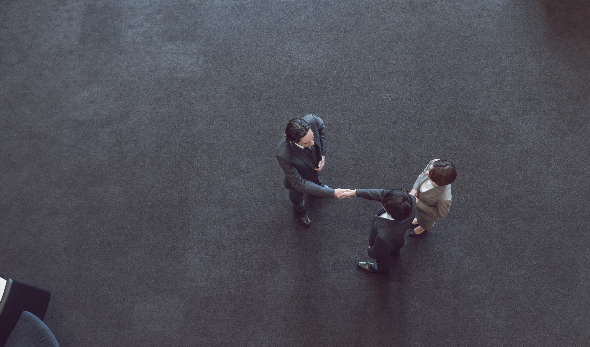 Aerial view of two people shaking hands standing next to a woman