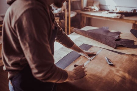 A man measuring leather on a table