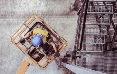 A worker wearing helmet standing in a cherry picker