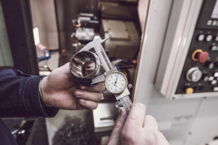 Metrology technician verifies the accuracy of manufacturing steel parts with a special caliper