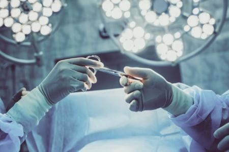 Closeup of gloved hands holding surgical scissors