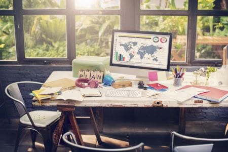 A desk with a bunch of papers and a monitor