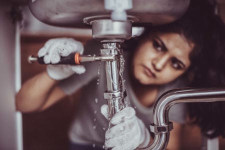 A plumber working on a sink pipe