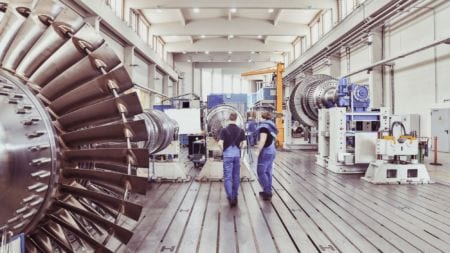 Workers assembling and constructing gas turbines in a modern industrial factory