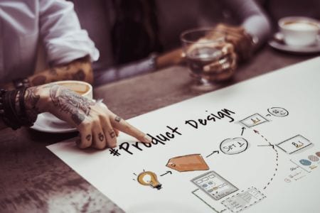 A person pointing to s product design on a table