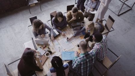 A group of people sitting around the table working on a project