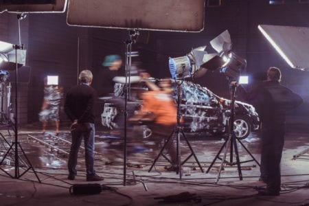 Blurred motion photo of producers filming a car on set.