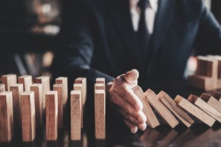 A businessman preventing wooden dominoes from falling