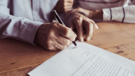 An elderly person signing a document