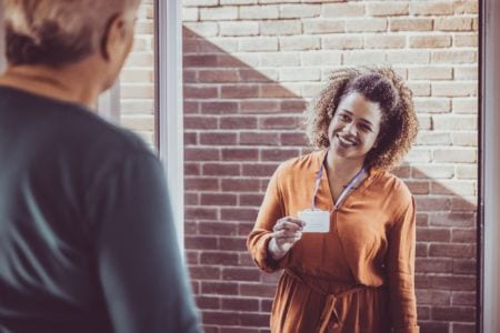 Social worker smiling and showing her name tag to a client