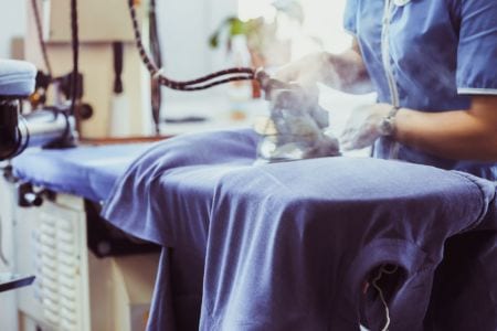 Textile care operative ironing a blue shirt