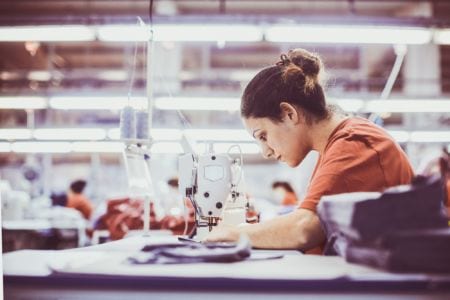Textile manufacturing operative working on a sewing machine