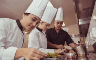 A chef mentoring two young women as part of on-the-job training