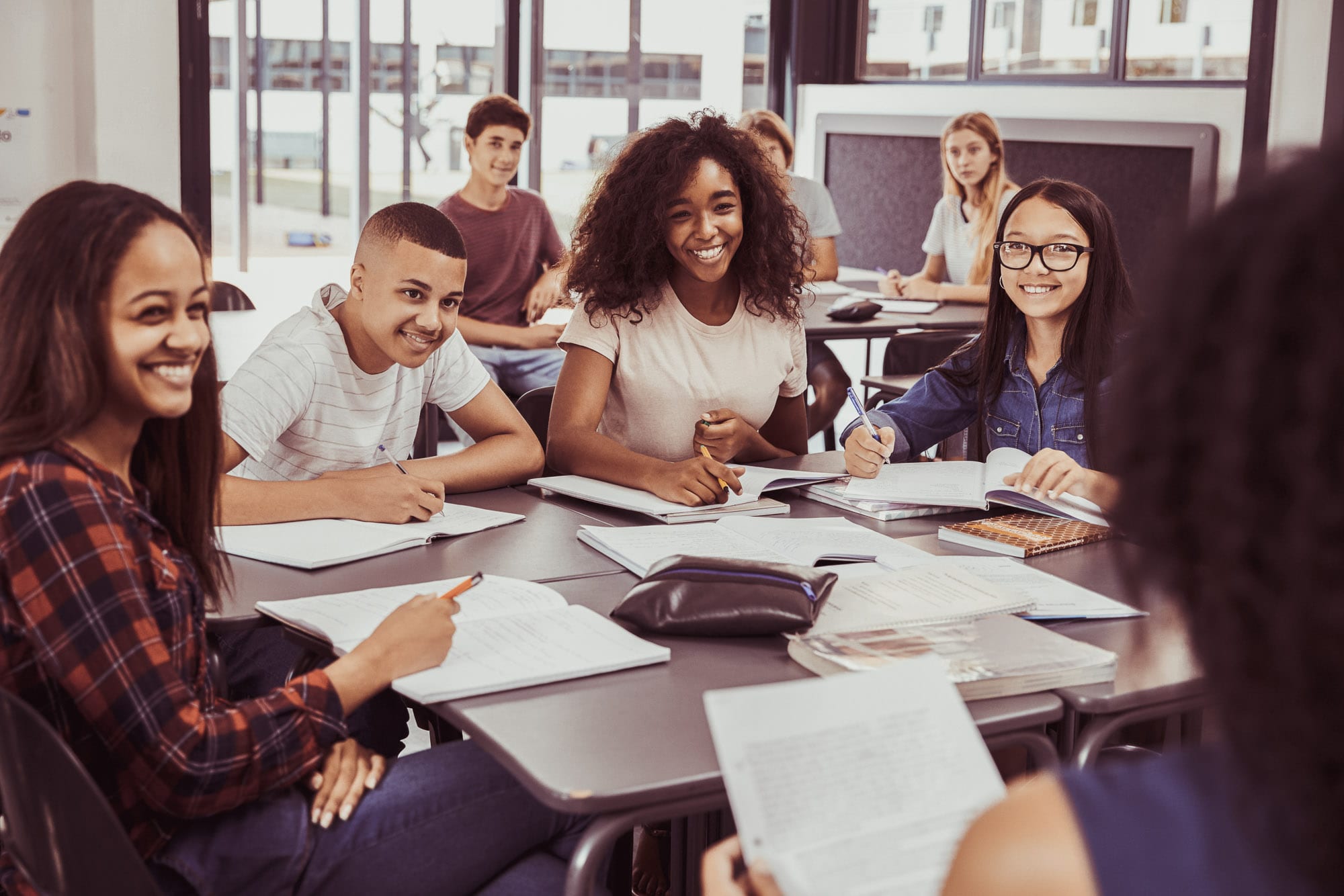 A group of students sitting around a table smiling. They are doing an apprenticeship which is helping to bridge the skills gap.