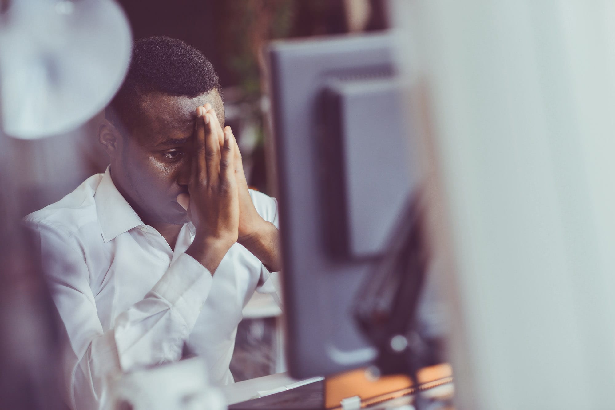 A stressed man looking at a pc screen