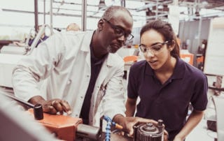 An older man mentoring an engineering student