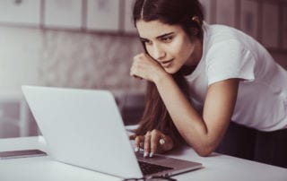 A young woman working on her degree apprenticeship on a laptop