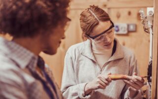 A student wearing safety glasses uses a screwdriver while working on a circuit board - benefits of work experience