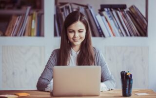 A young woman sitting in front of a laptop smiling